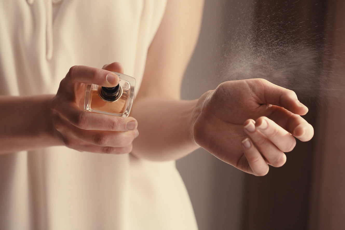 Frau sprüht Parfum auf Handgelenk