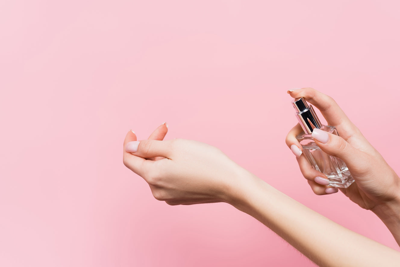 Parfum wird vor einem rosa Hintergrund auf eine Hand aufgetragen 