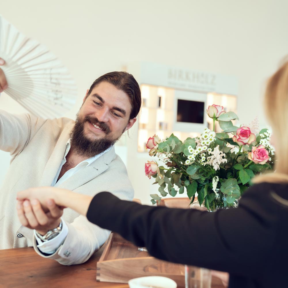 Philip Birkholz fächert einer Frau Parfum vom Handgelenk zu